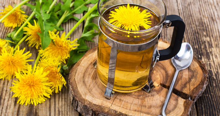 Kräutertee auf einer Holzscheibe serviert zusammen mit Löwenzahn